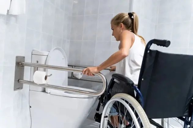 An occupational therapist supporting a wheelchair user with bathroom grab rails at home
