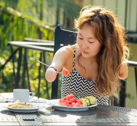A woman eating a meal independently using an adapted grip